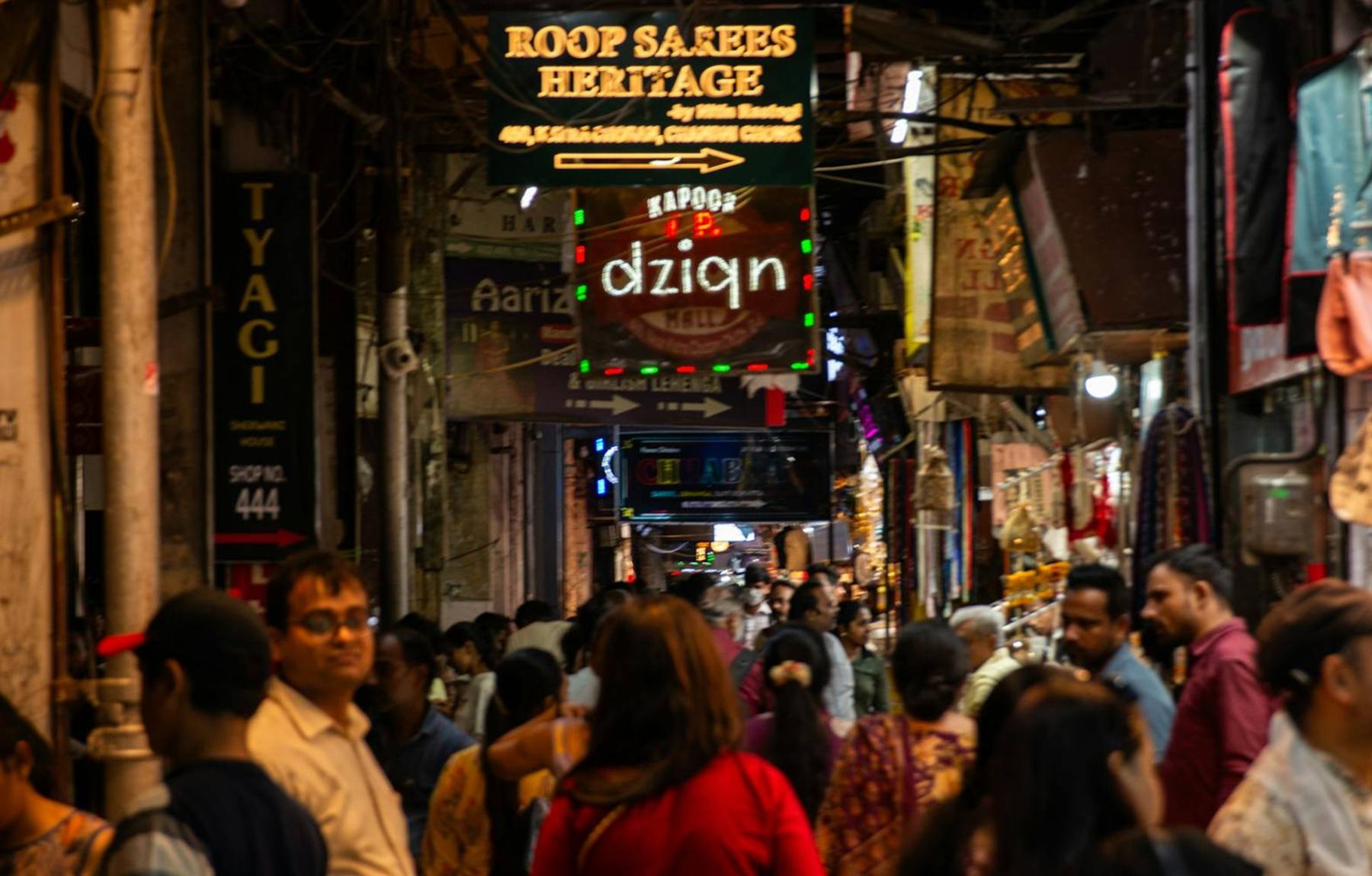 Indian market street lined with illuminated shop name boards at night