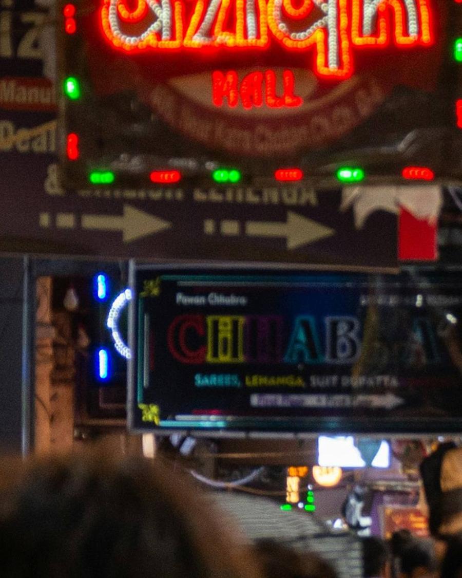Indian shop name boards illuminated above a market street